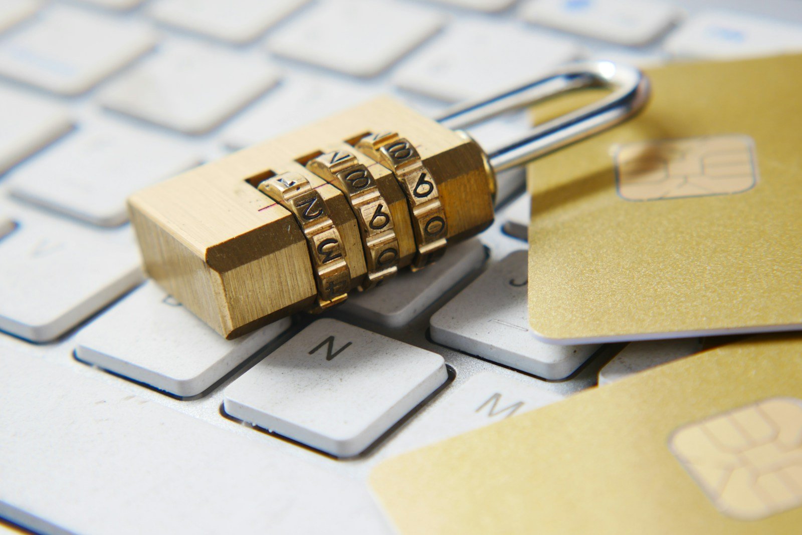 A combination padlock and bank cards resting on a computer keyboard, representing personal and financial data exposure