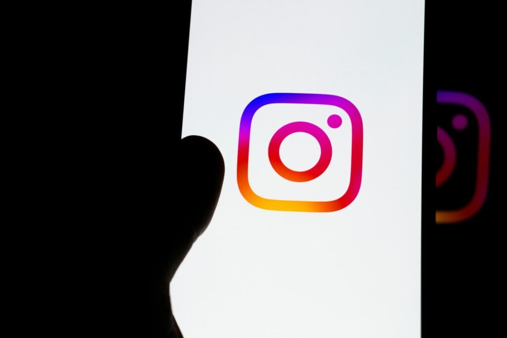 A hand holding a phone showing the Instagram logo on screen, representing the decision to buy Instagram followers