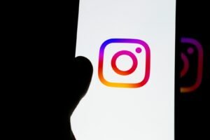 A hand holding a phone showing the Instagram logo on screen, representing the decision to buy Instagram followers