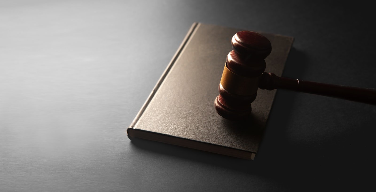 Wooden judge's gavel resting on a closed book, representing the legal side of bidding on competitor trademarks in Google Ads