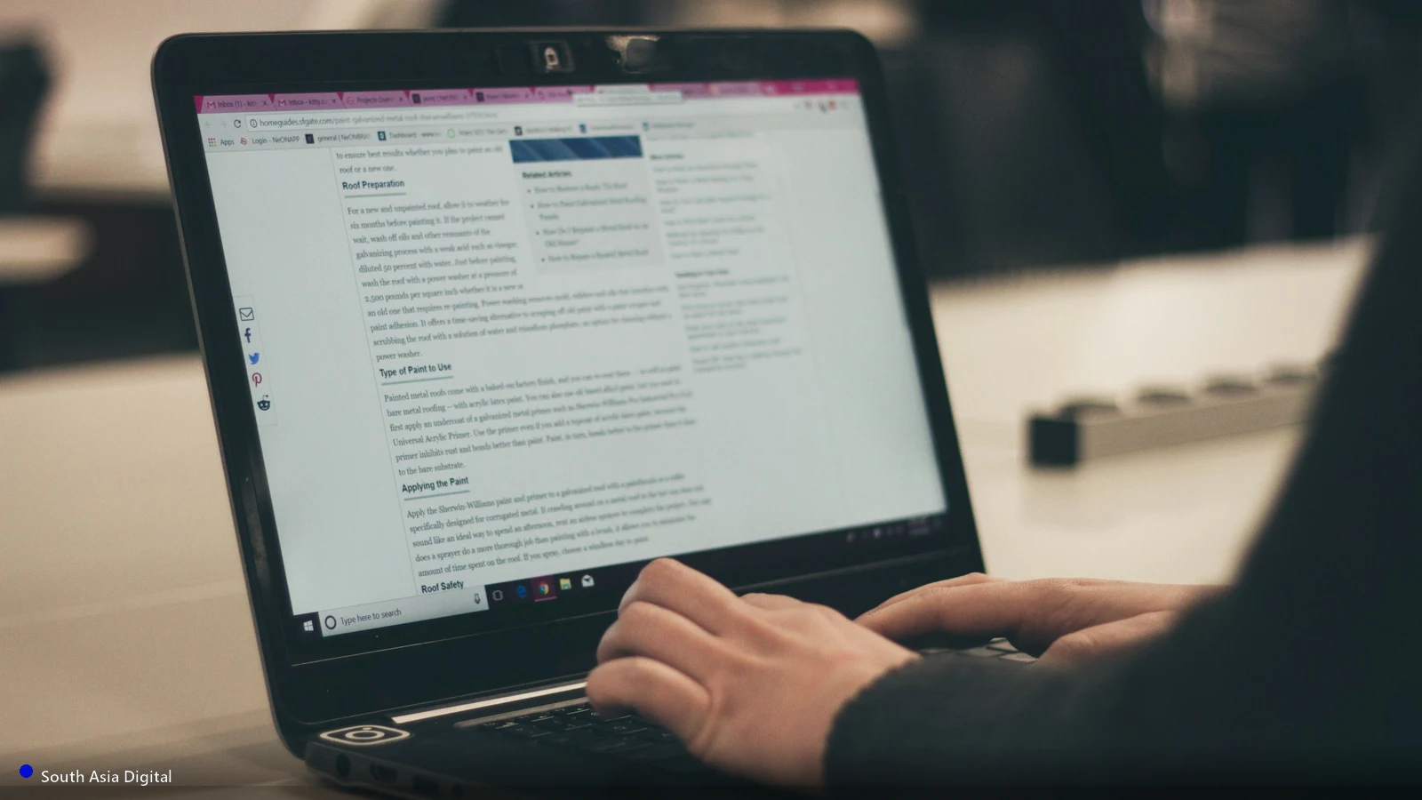 Hands typing on a laptop keyboard while researching and writing web content